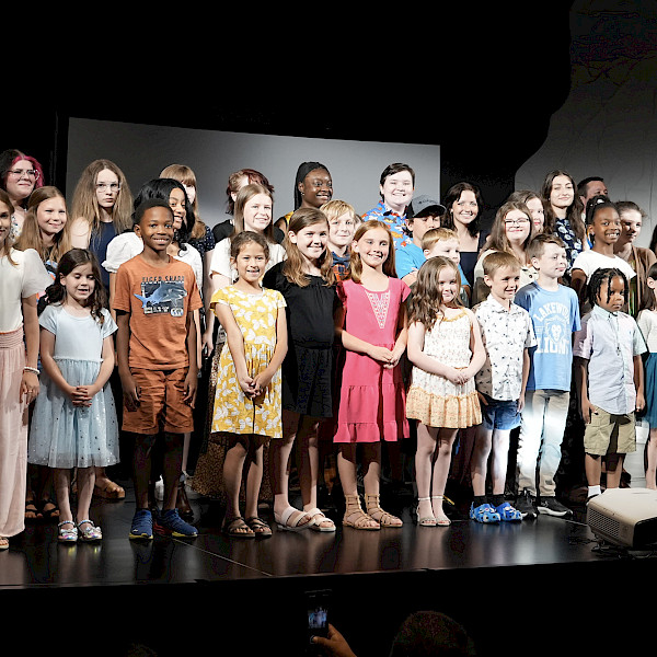 Photo of a group of children smiling on a stage.