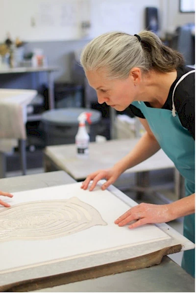 Photo of Tricia Wright working on a print in an art studio.